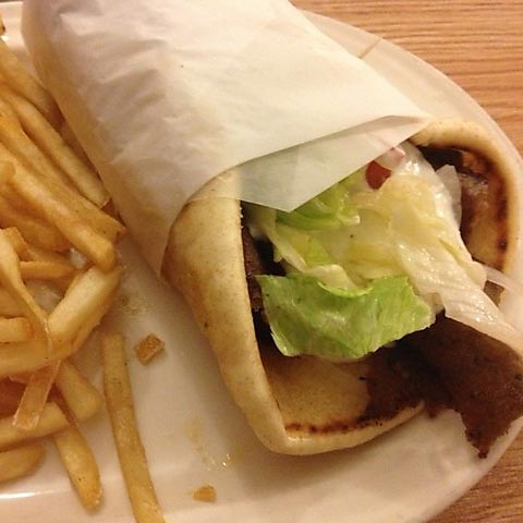 An authentic gyro wrapped in paper, served with fries.