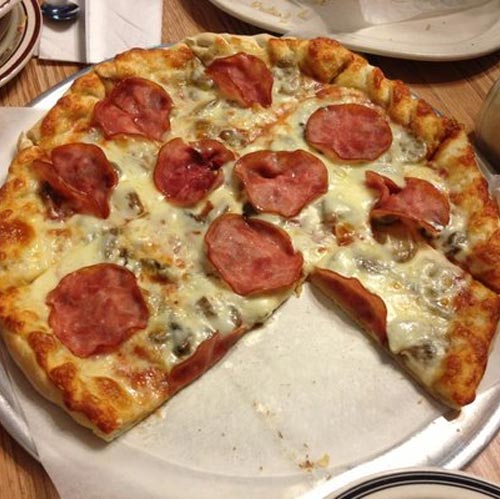 A pepperoni and mushroom pizza, one slice taken.